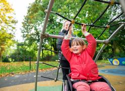 cheerful image of young girl in wheelchair playing at a park