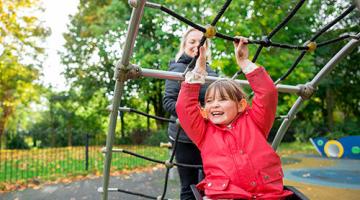 cheerful image of young girl in wheelchair playing at a park